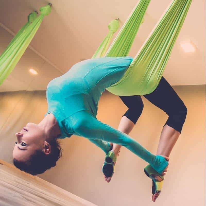 Concentrated focused woman performing inverted butterfly pose during aerial  yoga group workout in fitness studio, hanging upside down in hammock with  arms twisted.. Stock Photo | Adobe Stock